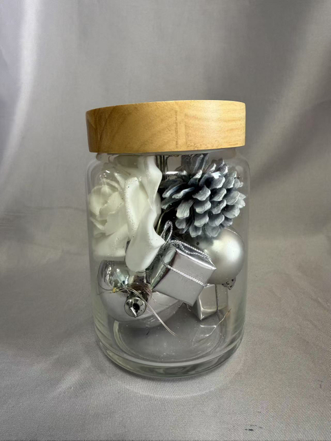 保留的花束在密封的玻璃罐中，带有银闪烁的线灯（AA×2电池供电），上面装饰着白玫瑰，银浆果，球体，礼品盒，松果和干草